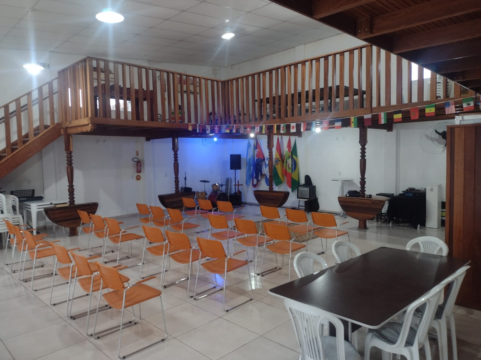 Salão da igreja com mezanino de madeira, cadeiras e mesas